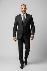 Man wearing black peak lapel three-piece suit with tailored fit for formal events.
